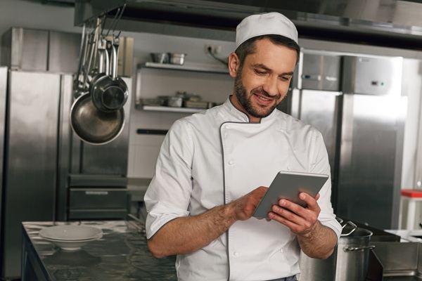 Cuisinier consultant un rapport d'audit d'hygiène sur tablette